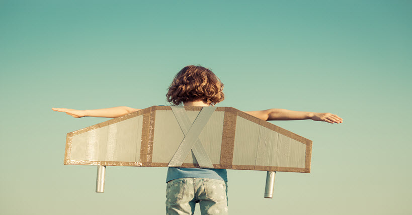 Child wearing toy wings against summer sky background