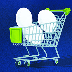 A shopping cart with different sized eggs in it. 