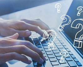 Close-up of hands typing on a laptop with floating question marks.