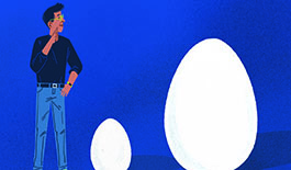 Man looking at 2 eggs. 1 big 1 small.