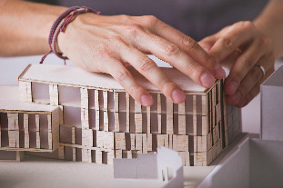 Modèle architectural d'un bâtiment étant construit par des mains